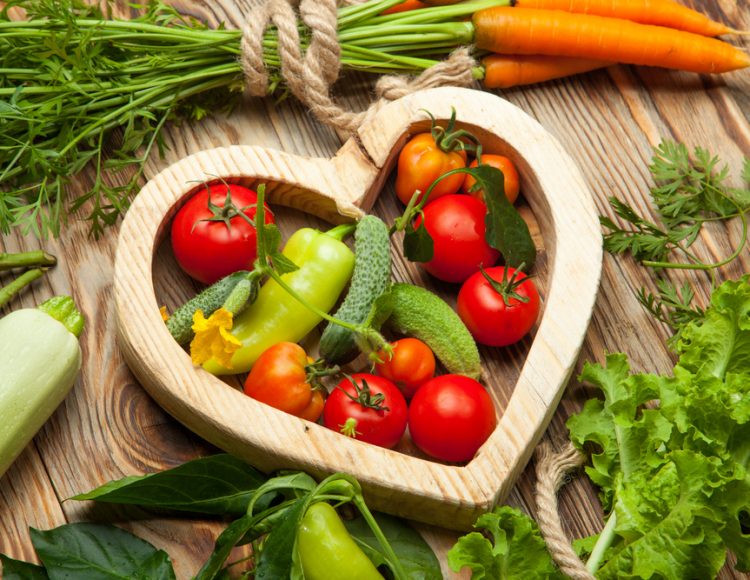 Wooden heart outline with vegetables inside and out.