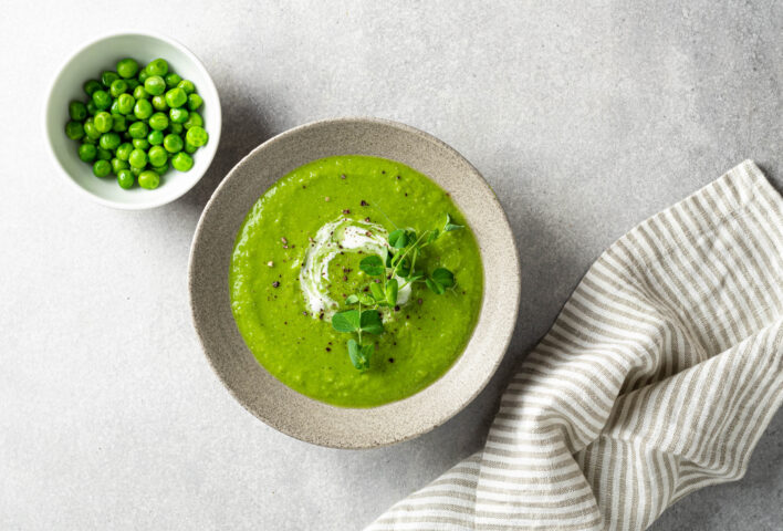 Thai Green Pea Soup garnished with pea shoots on a grey background